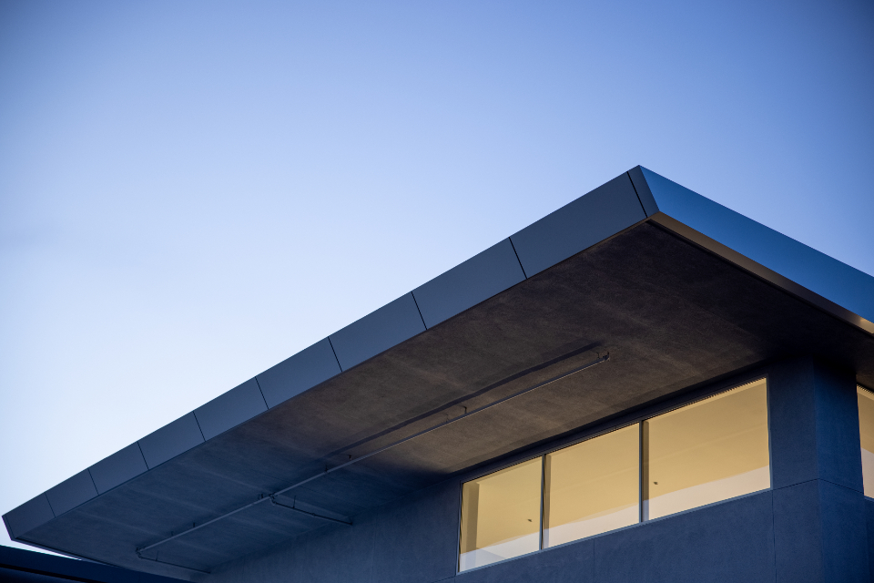 Cantilevered roofline of a modern building against a clear evening sky