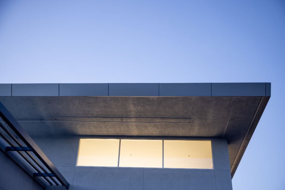 New upper storey cantilevered over the floor below, windows lit at dusk