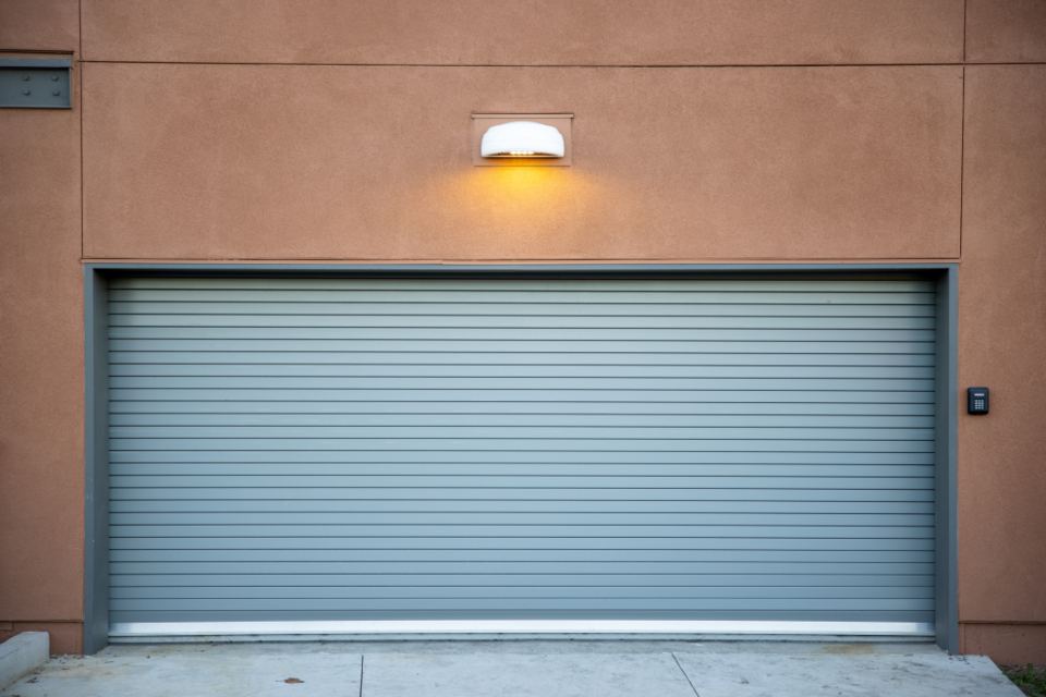 Garage door lit by a wall lamp at dusk