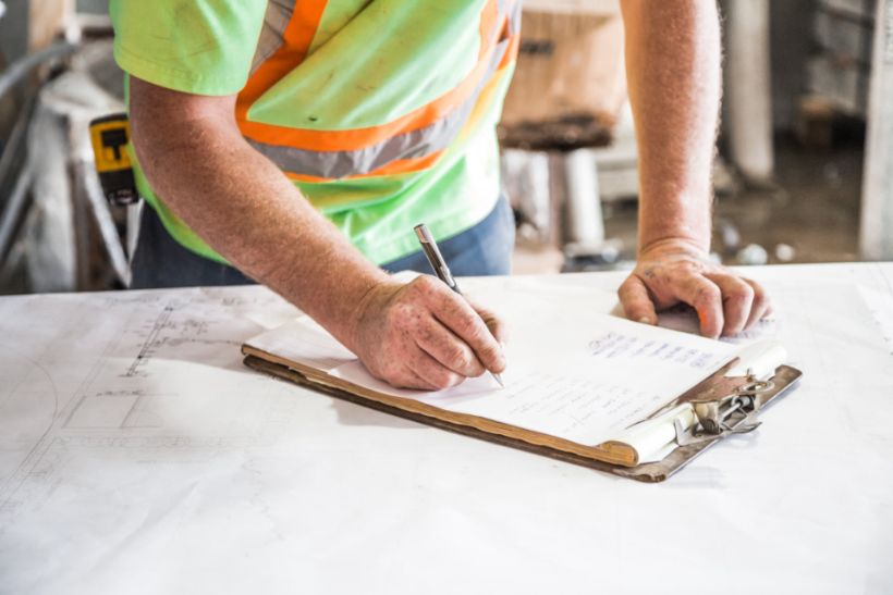 Builder checking drawings against a clipboard