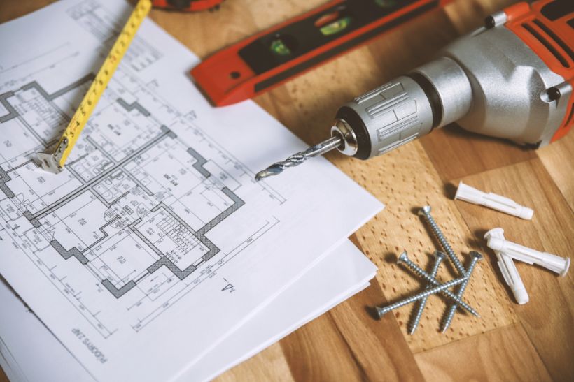 Floor plan on a workbench with a level and drill