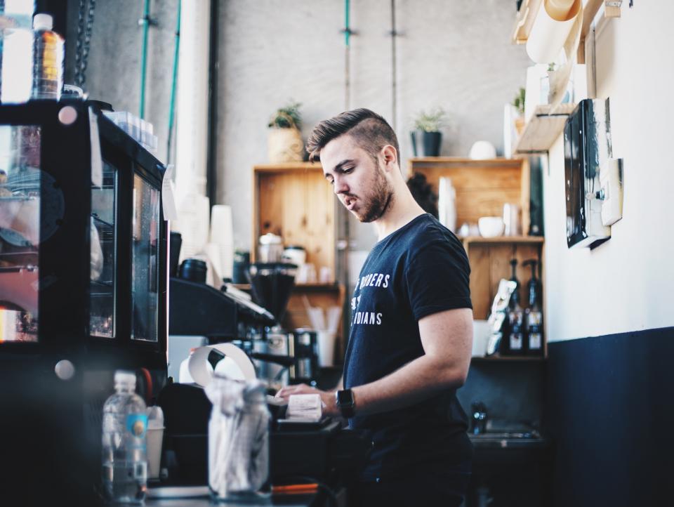 Barista working an espresso machine behind a cafe counter