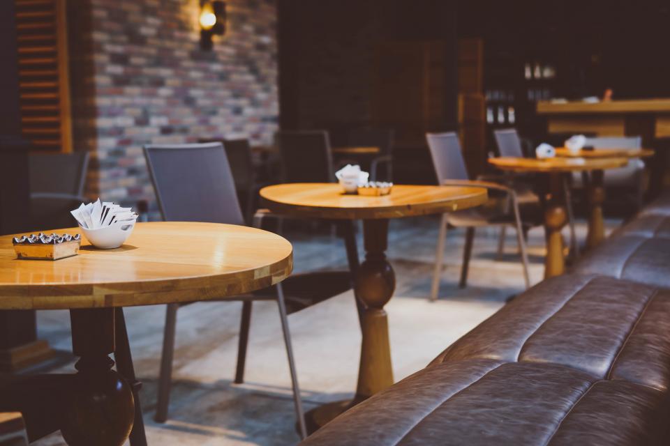Cafe interior with round timber tables and a leather banquette